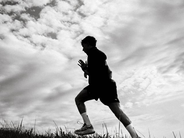 Coureur en silhouette sur une crête, ciel nuageux
